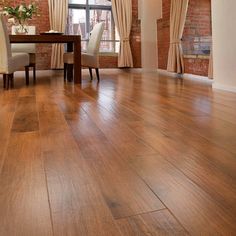 an empty room with hard wood floors and brick walls