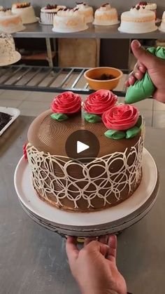 a person is decorating a cake with roses on the icing and frosting