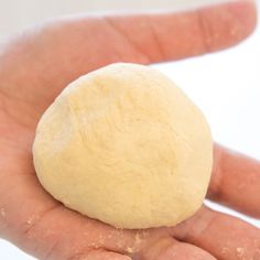 a hand holding a ball of dough in it's palm