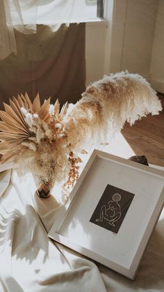 a dog standing next to an art piece on a bed with white sheets and drapes