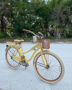 an old yellow bicycle is parked in front of some trees