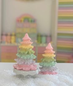 two small plastic trees sitting on top of a white table next to each other in front of a mirror