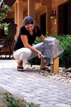 a woman kneeling down to place a rock on top of a bench