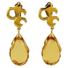 YVES SAINT LAURENT vintage gold toned dangling earrings (clip-on) featuring a gorgeous arabesque design embellished with a large resin drop. Marked YSL Made in France. Indicative measurements : height approx. 7.5 cm (2.95 inches) / max. width approx. 2.2 cm (0.87 inch). NOTES - This is a preloved vintage item, therefore it might have imperfections. - Colors may differ slightly from actual product appearance due to differences in lighting conditions. - As a buyer, you are fully responsible for cu Big Gold Dangle Earrings, Ysl Earrings, Ysl Vintage, Kendall Jenner Chanel, Saint Laurent Vintage, Arabesque Design, St Laurent, Christian Lacroix, Antique Earrings