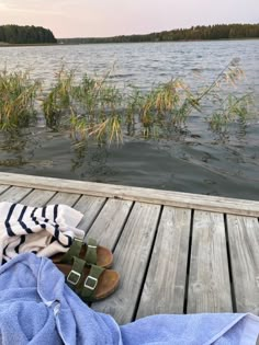 a pair of sandals sitting on top of a wooden dock next to a body of water