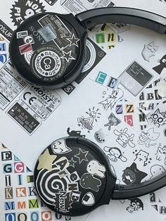 two black headphones sitting on top of a table covered in stickers and paper