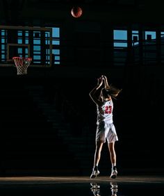 a basketball player jumping up to dunk the ball into the air with her hands