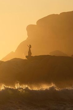 a person standing on top of a rock near the ocean