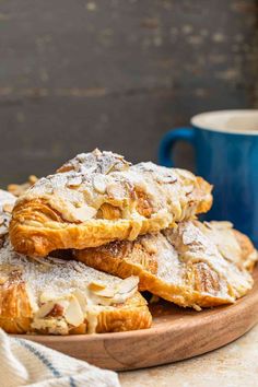 several pastries piled on top of each other in front of a blue cup and saucer