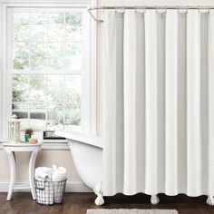 a bathroom with a bathtub, shower curtain and rug in front of the window