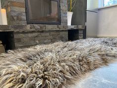 a living room with a stone fireplace and large furry rug