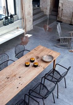 a wooden table sitting on top of a cement floor next to chairs and a bench