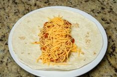 a tortilla covered in cheese on top of a white plate next to a granite counter