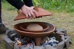 a person placing a pot on top of a fire pit