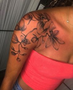 the back of a woman's shoulder with flowers tattooed on her arm and chest