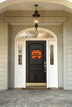 a black front door with an orange pumpkin sign on it's side and the words happy halloween