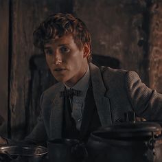 a man in a suit sitting at a table with pots and pans on it