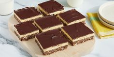 several pieces of cake sitting on top of a wooden cutting board next to a glass of milk