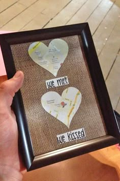 someone is holding up a framed photo with two hearts on it