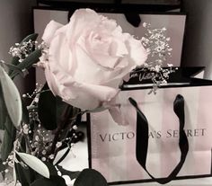 a pink rose sitting on top of a table next to a shopping bag and flowers