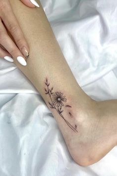 a woman's foot with a small flower tattoo on the left side of her leg