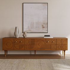 an art deco sideboard with two vases on top and a painting above it