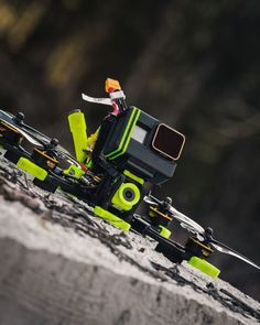 a yellow and black remote control vehicle sitting on top of a rock