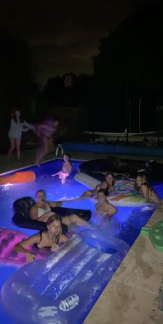 people are in an inflatable pool at night