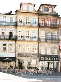 the building has many windows and balconies on it's sides, along with tables and chairs