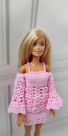 a doll wearing a pink crocheted dress and holding her hand on her hip