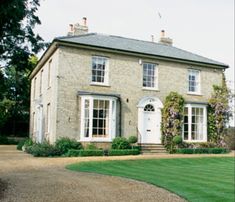 a large brick house sitting on top of a lush green field