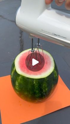 a watermelon sitting on top of an orange piece of paper next to a white object