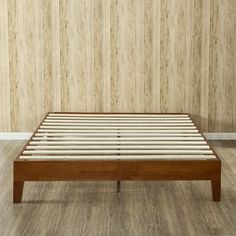 a wooden bed frame in front of a wall with wood planks on the floor