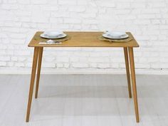 a table with two plates on it in front of a white brick wall and wooden legs