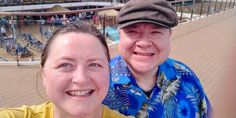 a man and woman taking a selfie in front of an outdoor swimming pool on a cruise ship