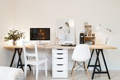 a desk with two chairs and a computer on top of it in a white room