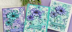 two cards with blue flowers on them sitting next to some purple and green paper work