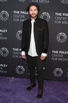 the paley center for media's purple carpeted event with a bearded man in a black suit and white shirt