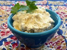 a blue bowl filled with mashed potatoes and garnished with parsley