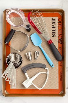 the best baking tools every baker needs in their kitchen are on this tray with text overlay that reads, the best baking tools every baker needs