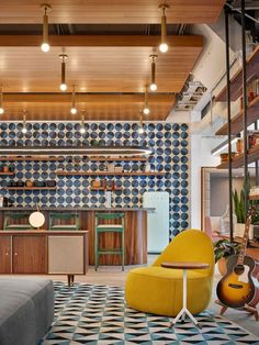 a living room filled with furniture and lots of lights hanging from the ceiling next to a kitchen