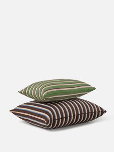 three pillows stacked on top of each other in different colors and sizes, one with a striped pattern