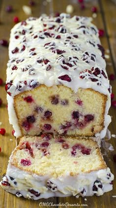 a loaf of cranberry pound cake with white frosting and fresh cherries