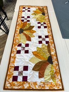 an orange and white table runner with leaves on it