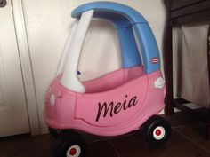 a pink and blue toy car sitting on top of a floor next to a wall