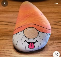 a rock painted with an image of a gnome's head and tongue sticking out