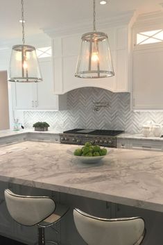 a large kitchen island with two stools and a bowl of fruit on the counter