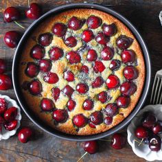 a cake with cherries on it sitting in a pan next to other desserts