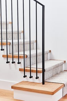 a set of stairs with black railings and wood treading on each handrail