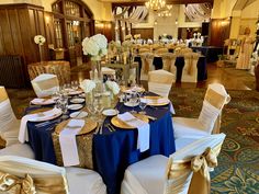 the tables are set up with gold and blue linens for an elegant wedding reception